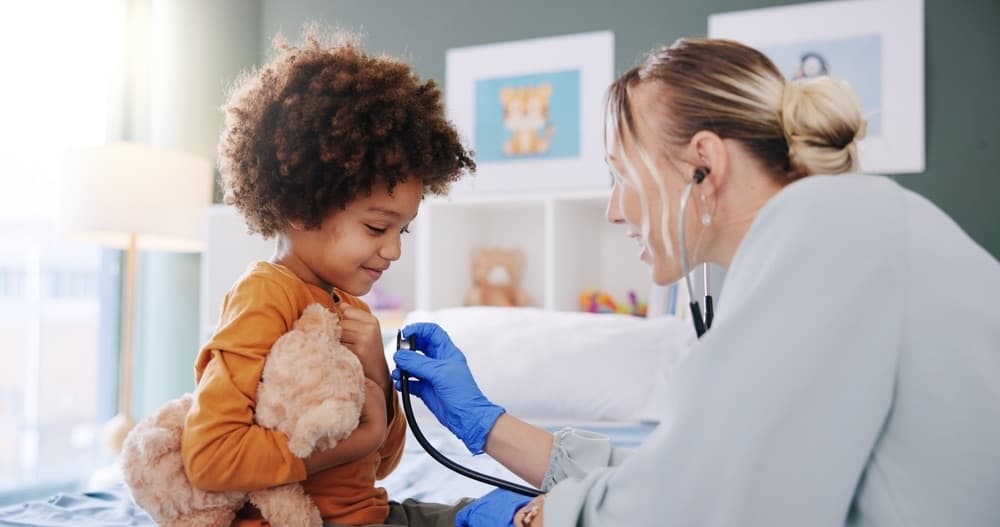 A doctor listening to a young child's heartbeat with a stethoscope