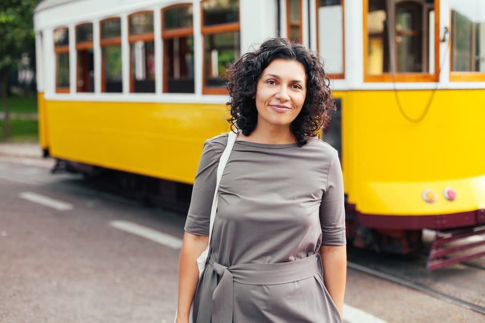 A woman standing in front of a yellow Lisbon tram