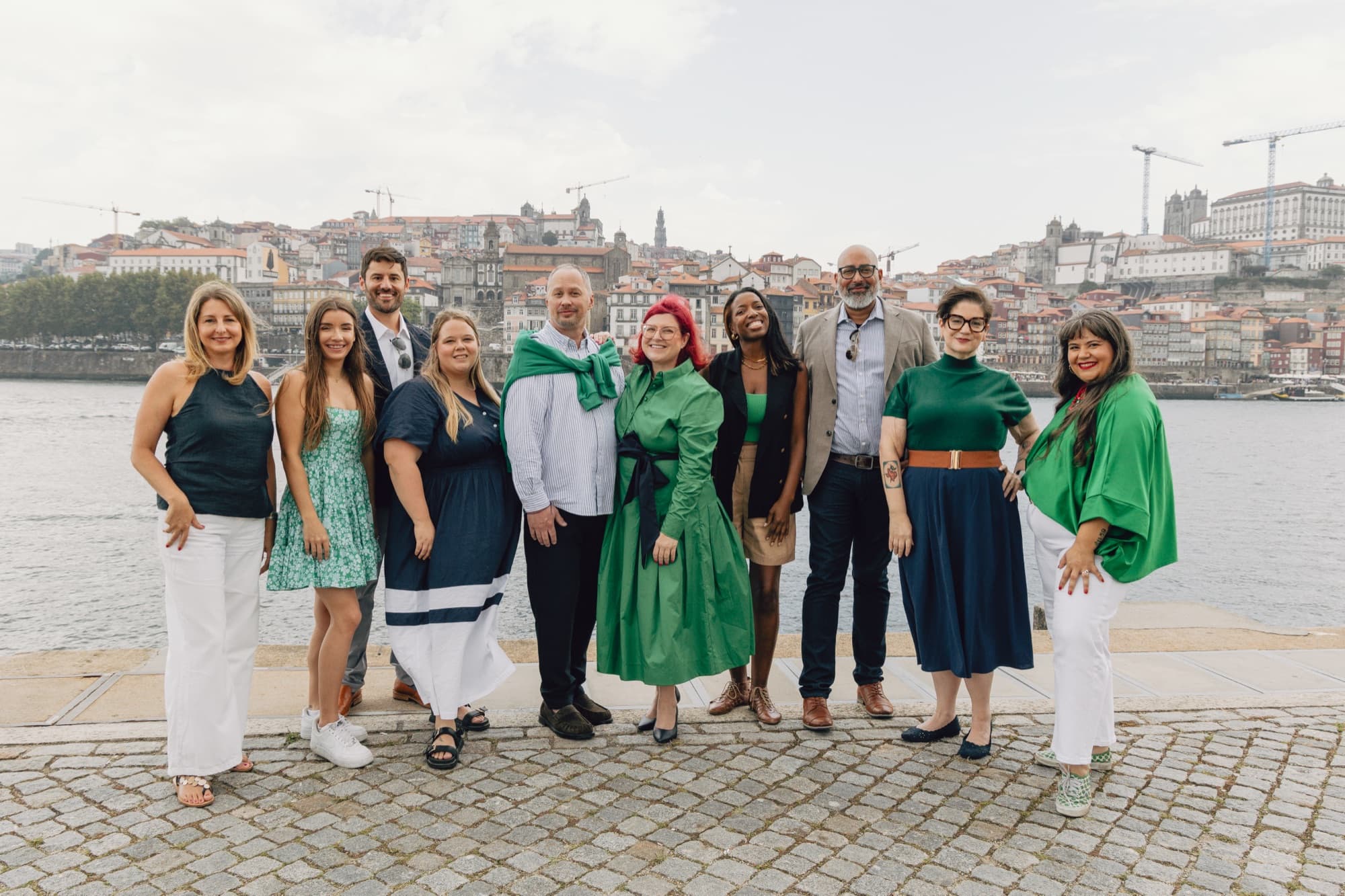 The Expatsi team standing together by a river, with a hillside city behind them