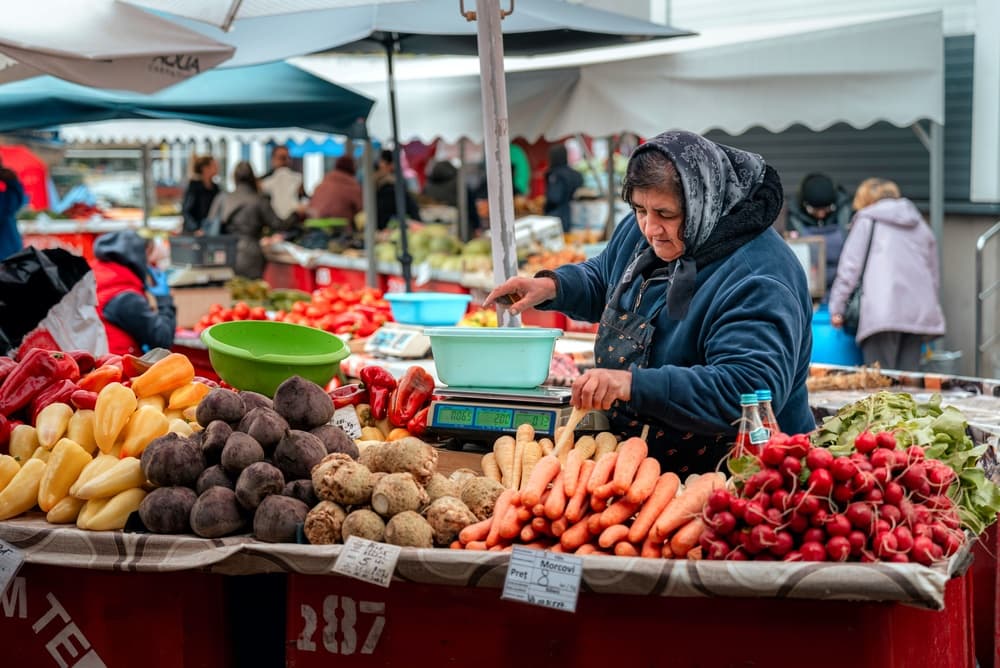 Babushka weighs fresh produce at market, Bucharest