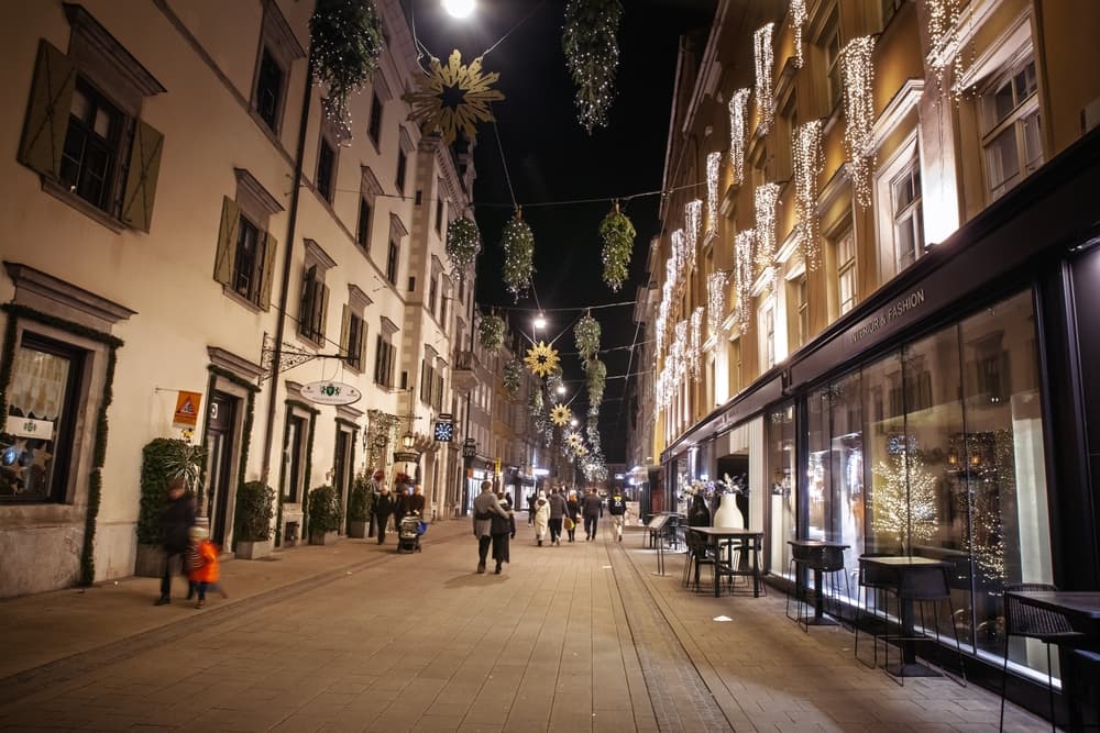 Locals stroll down residential town street at night, Graz
