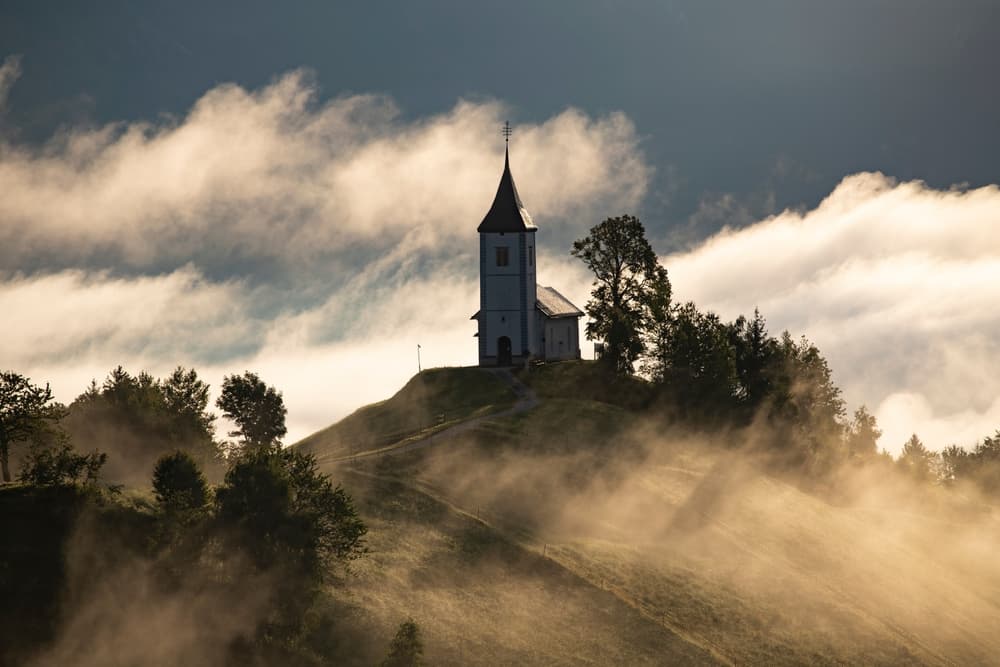 Chapel sits on hilltop during misty morning, Kranj