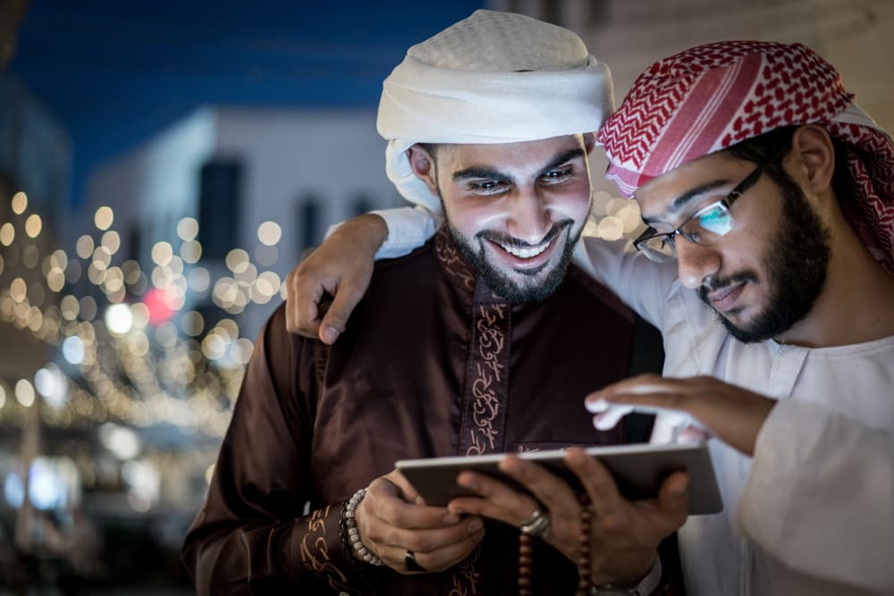 Arab men reviewing tablet together, Kuwait City
