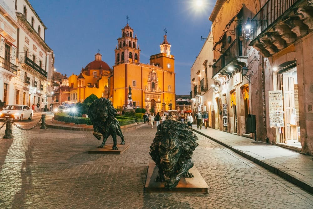 Lion stateu in foreground of image with local cathedral, La Paz