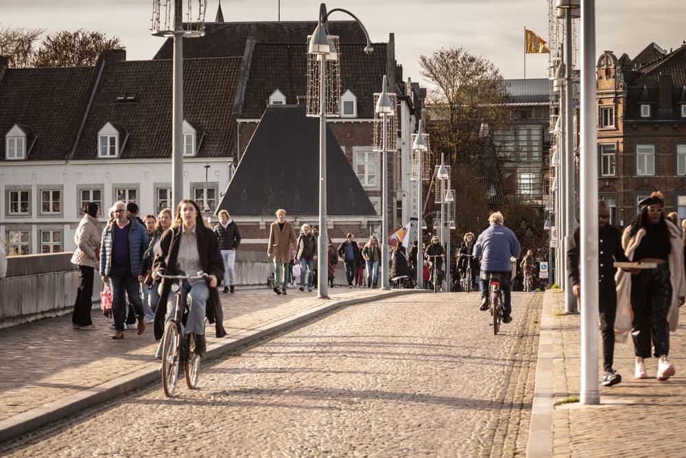 Cyclists crossing stone bridge over canal, Maastricht