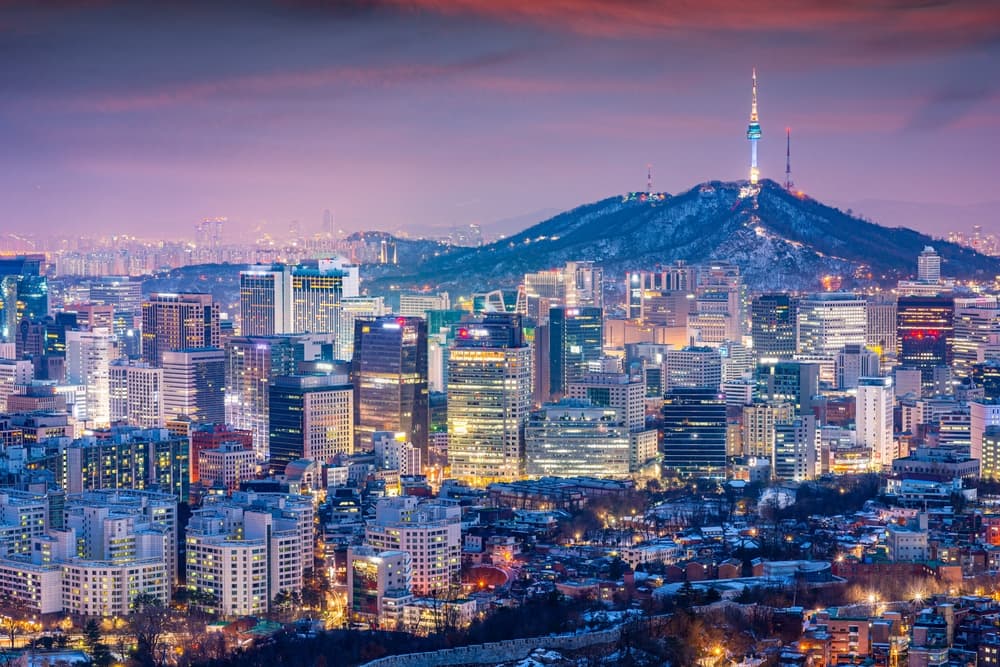 Downtown skyline lit at night against towering mountain, Seoul