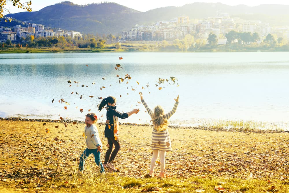 Children playing in the autumn leaves by the river, Tirana
