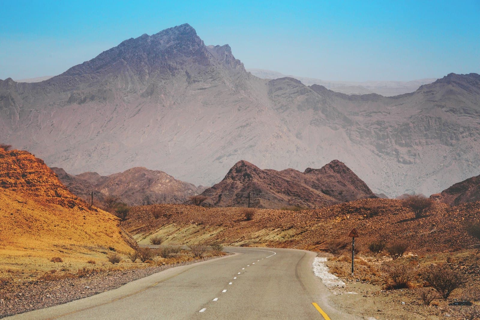 Empty road winding toward the Hajar Mountains in Oman