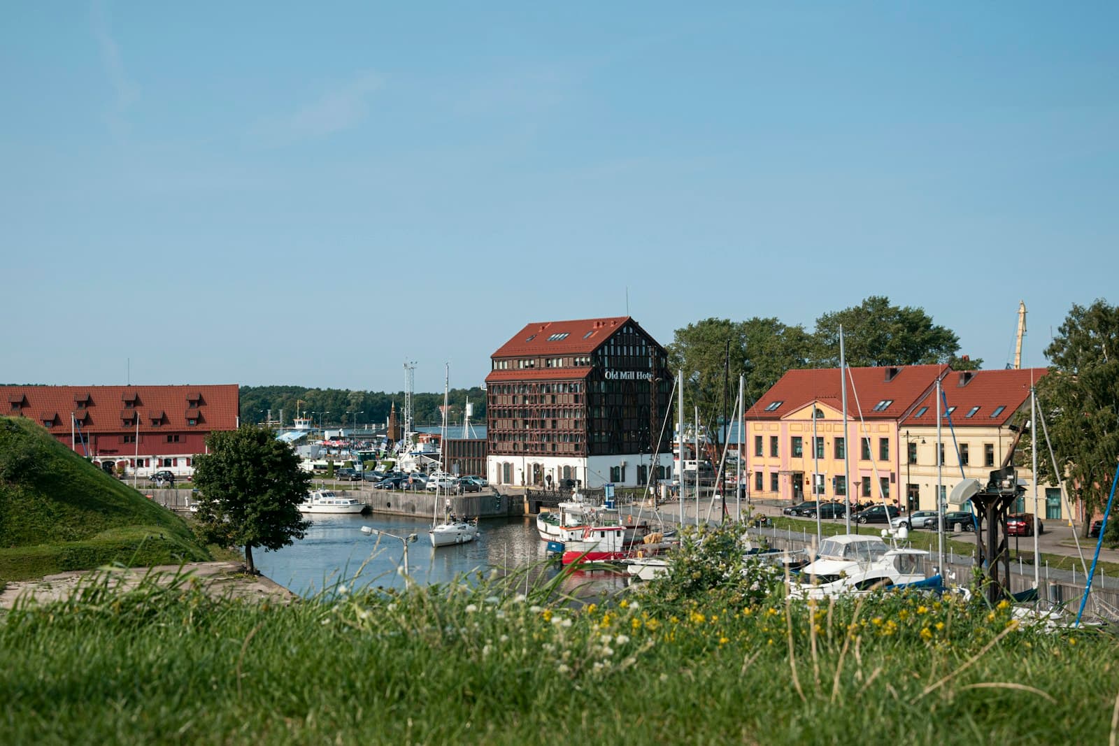 Sailboats in the Old Town harbor of Klaipėda on the Baltic coast, with red-roofed buildings behind