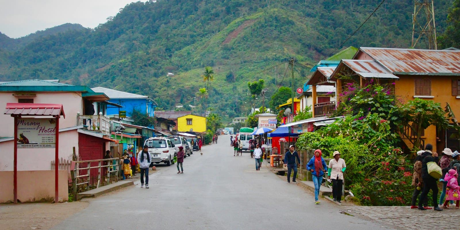 A main street in a green highland town in Madagascar, with colorful shops and people walking