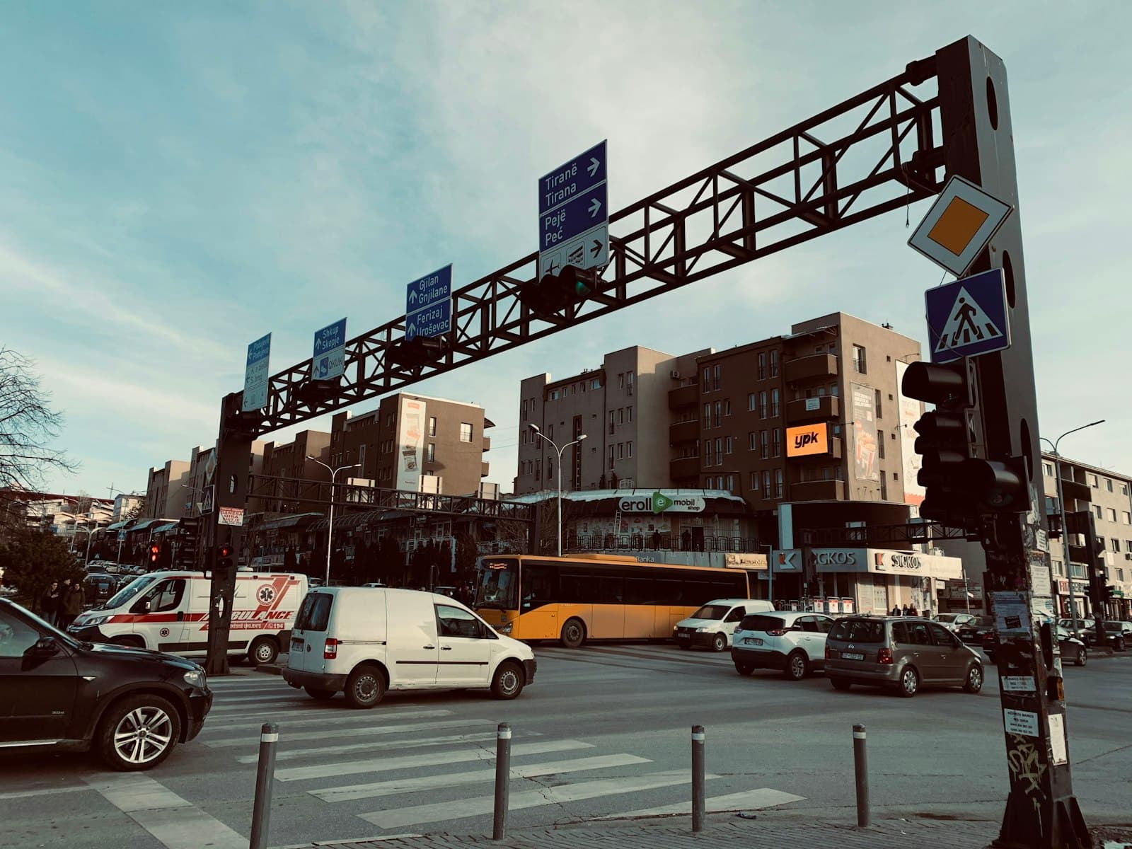 Busy intersection in Pristina with road signs pointing to Tirana, Peja and Skopje
