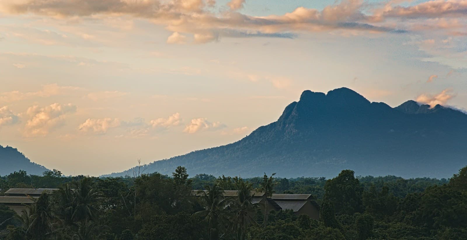 A forested mountain rising above the treetops near Kuching, Sarawak, at dusk