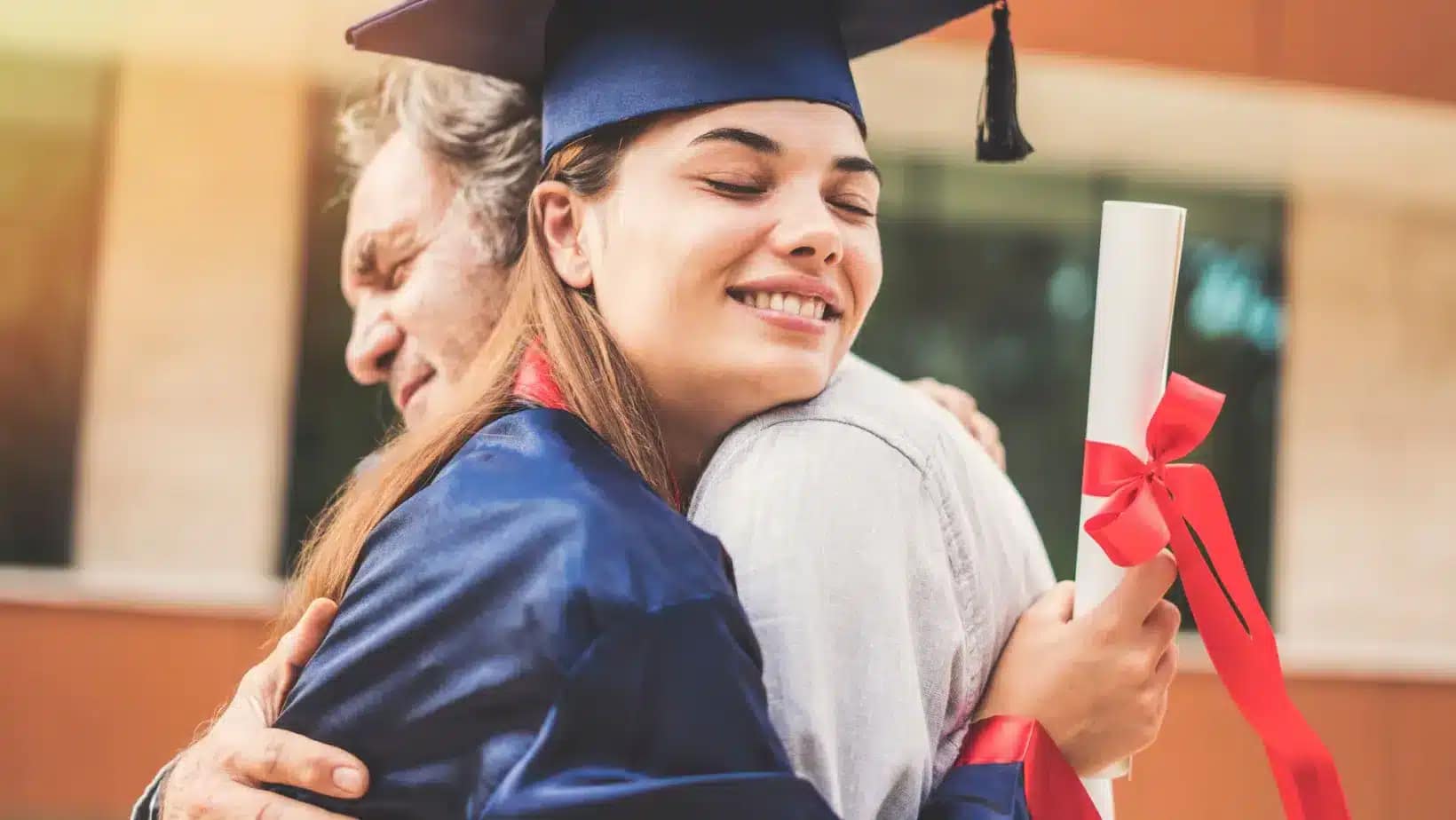 Graduate in cap and gown hugging her father