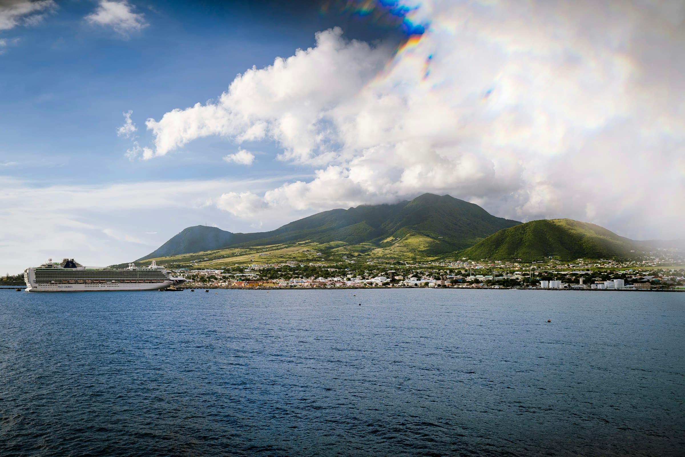 Basseterre waterfront on St. Kitts under green mountains, with a cruise ship docked at the port