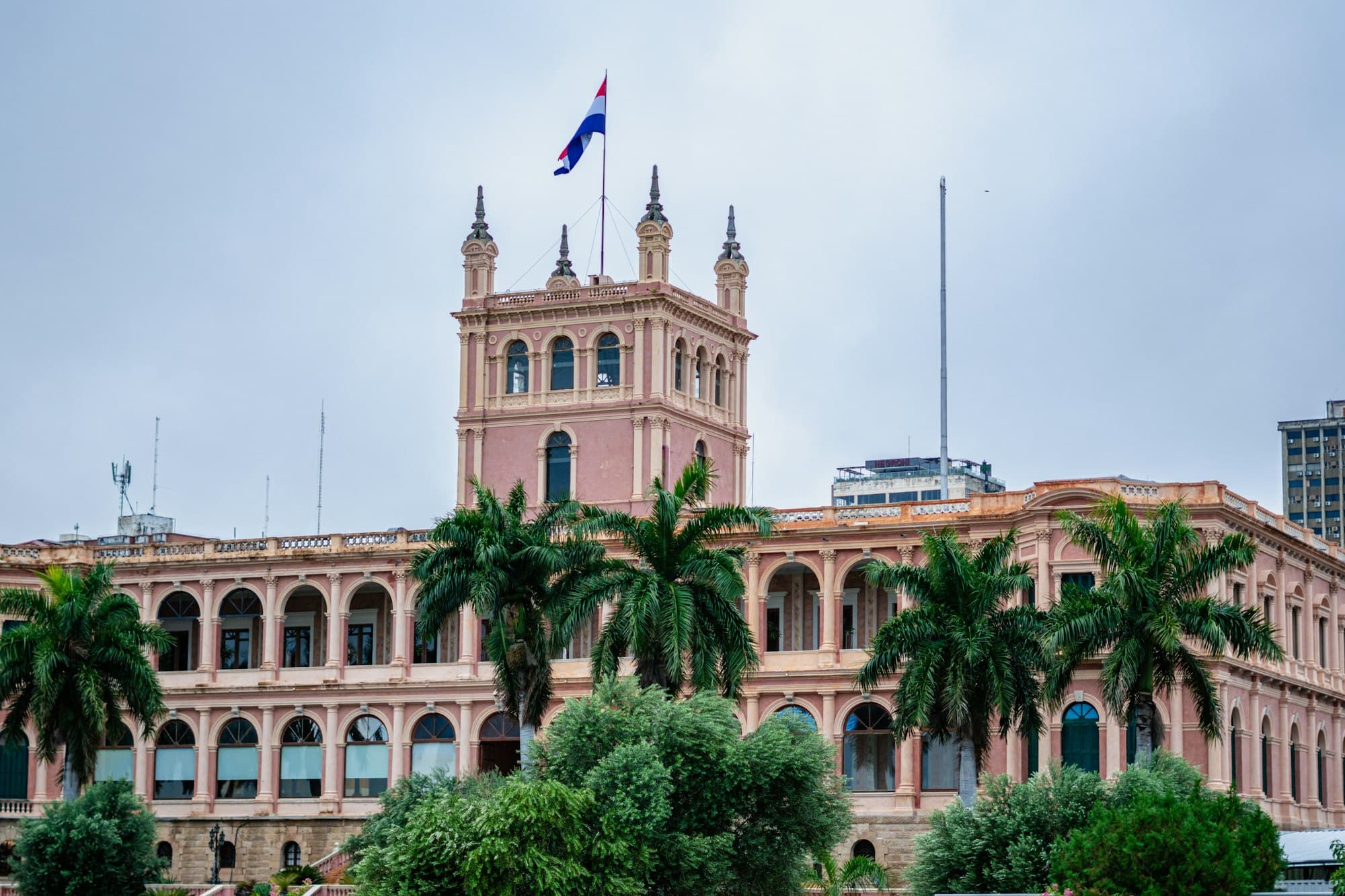 The Palacio de los López, Paraguay's pink government palace, with the national flag and palm trees in Asunción