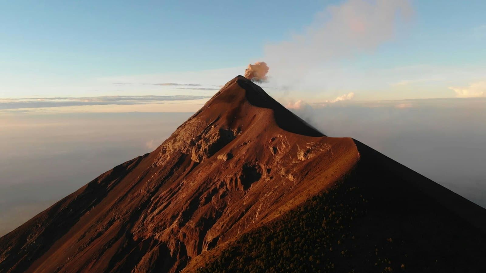 Volcán de Fuego's summit releasing a small plume of ash at sunrise, seen from Acatenango