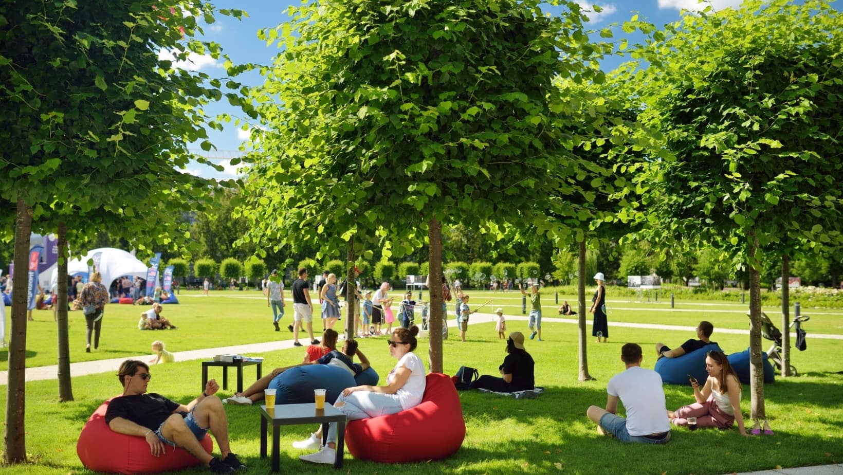 People relaxing on bean bags under the trees in a green park in Vilnius on a summer day