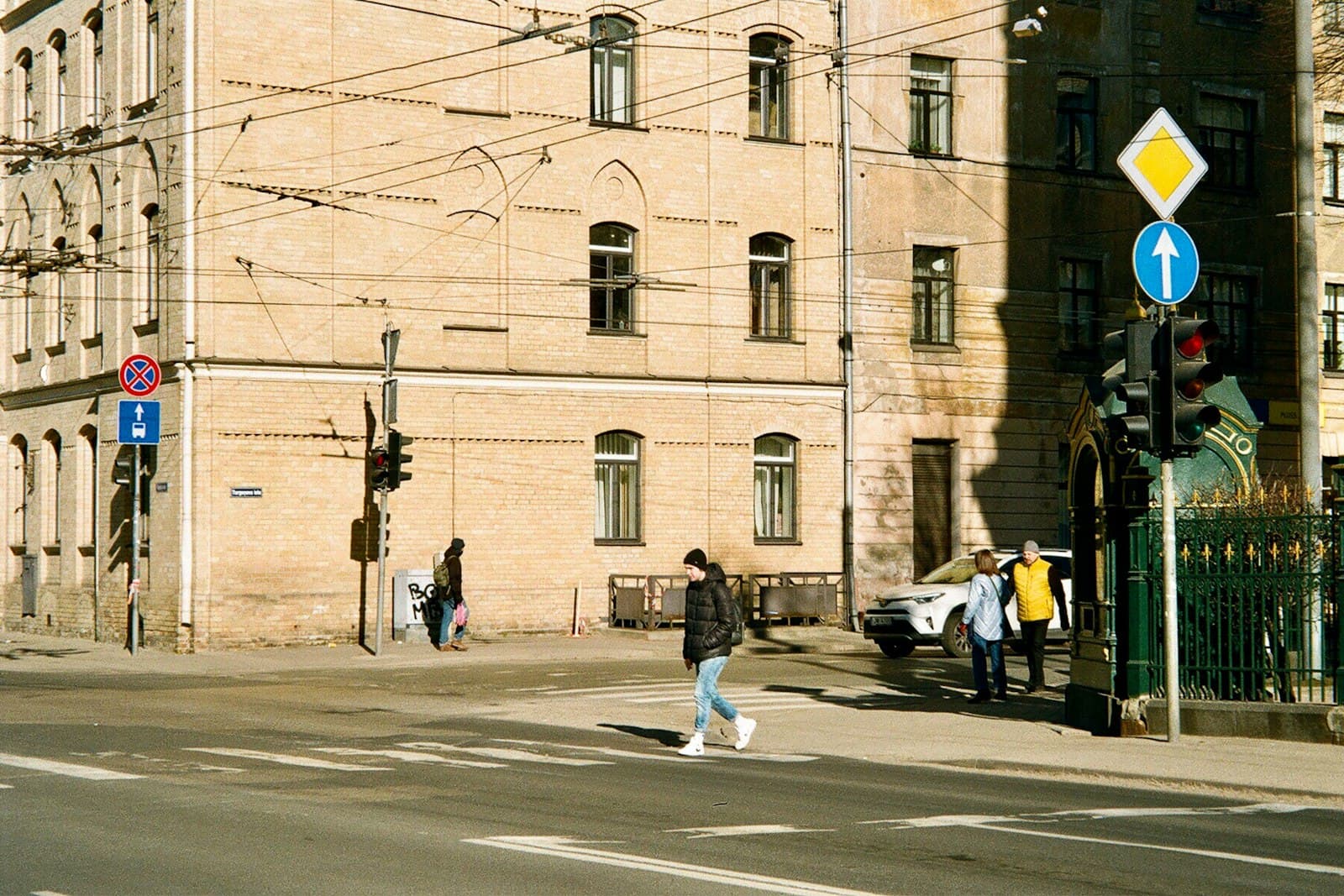 People crossing a sunny street corner in central Riga