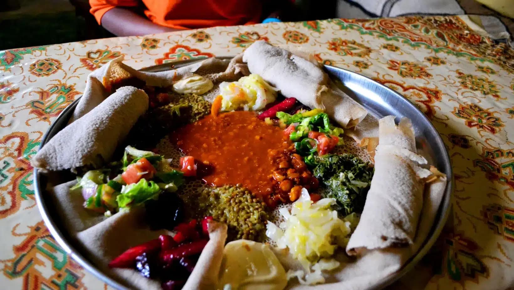 A shared platter of injera topped with lentil stews and vegetables