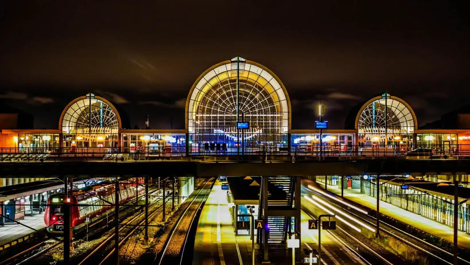 A Danish railway station lit up at night with trains at the platforms