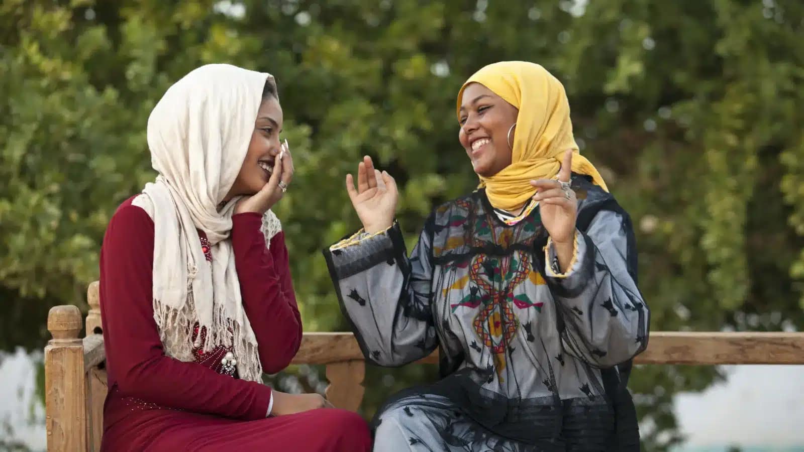 Two Egyptian women laughing together on a garden bench