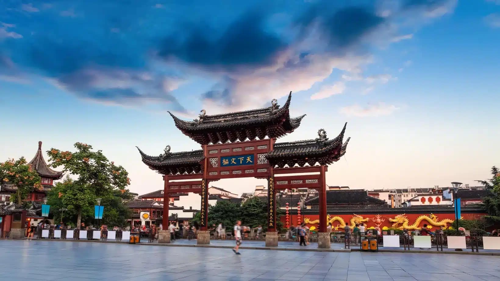A traditional red and gold gateway on a plaza in Nanjing at sunset