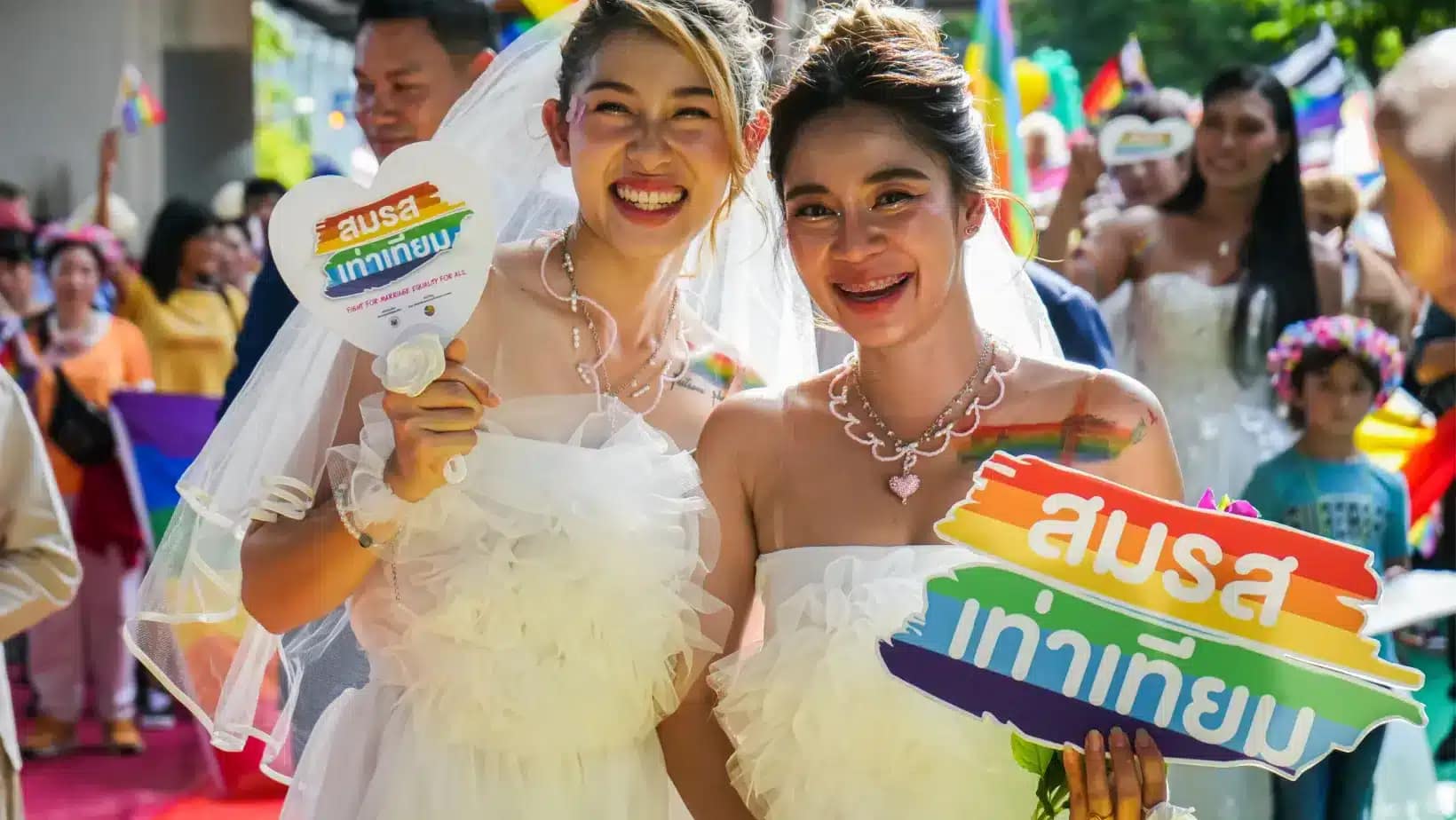 Two brides holding marriage equality signs at a celebration in Bangkok