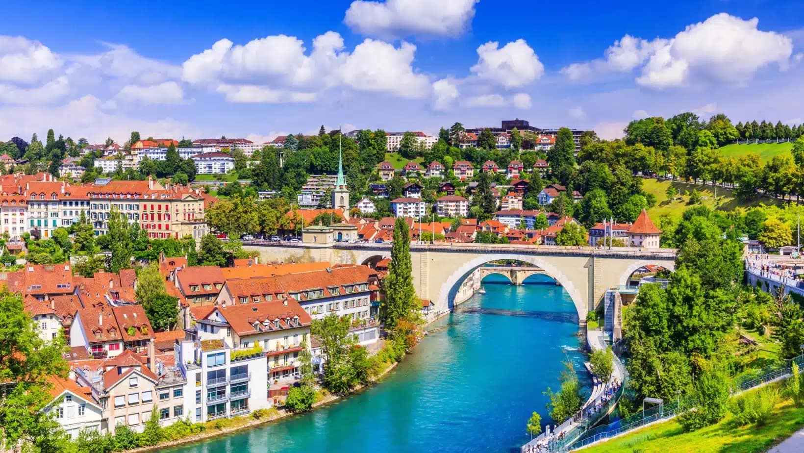 Bern's old town and a stone bridge over the turquoise Aare river on a sunny day