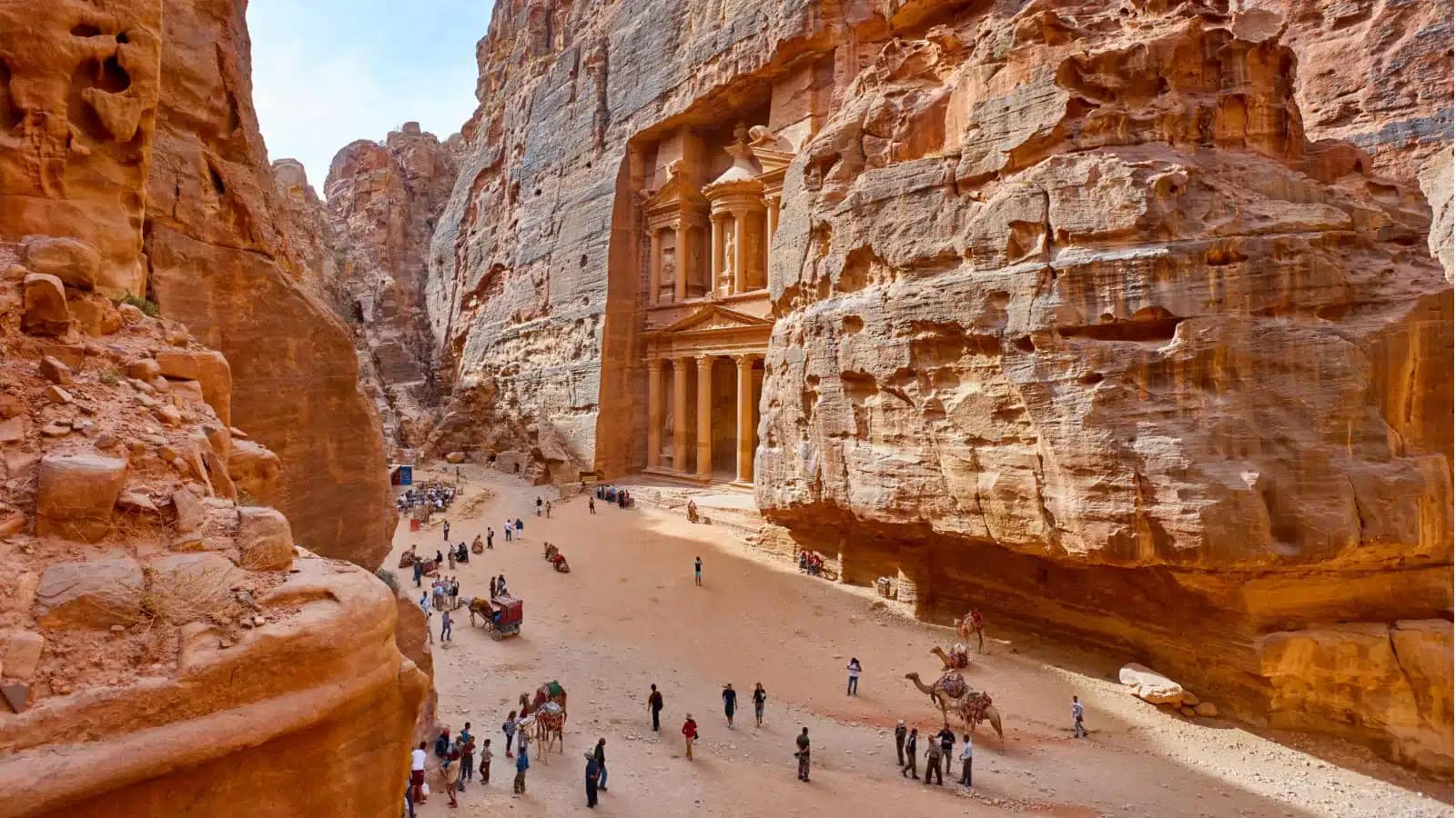 Visitors walking through the canyon toward the Treasury facade at Petra
