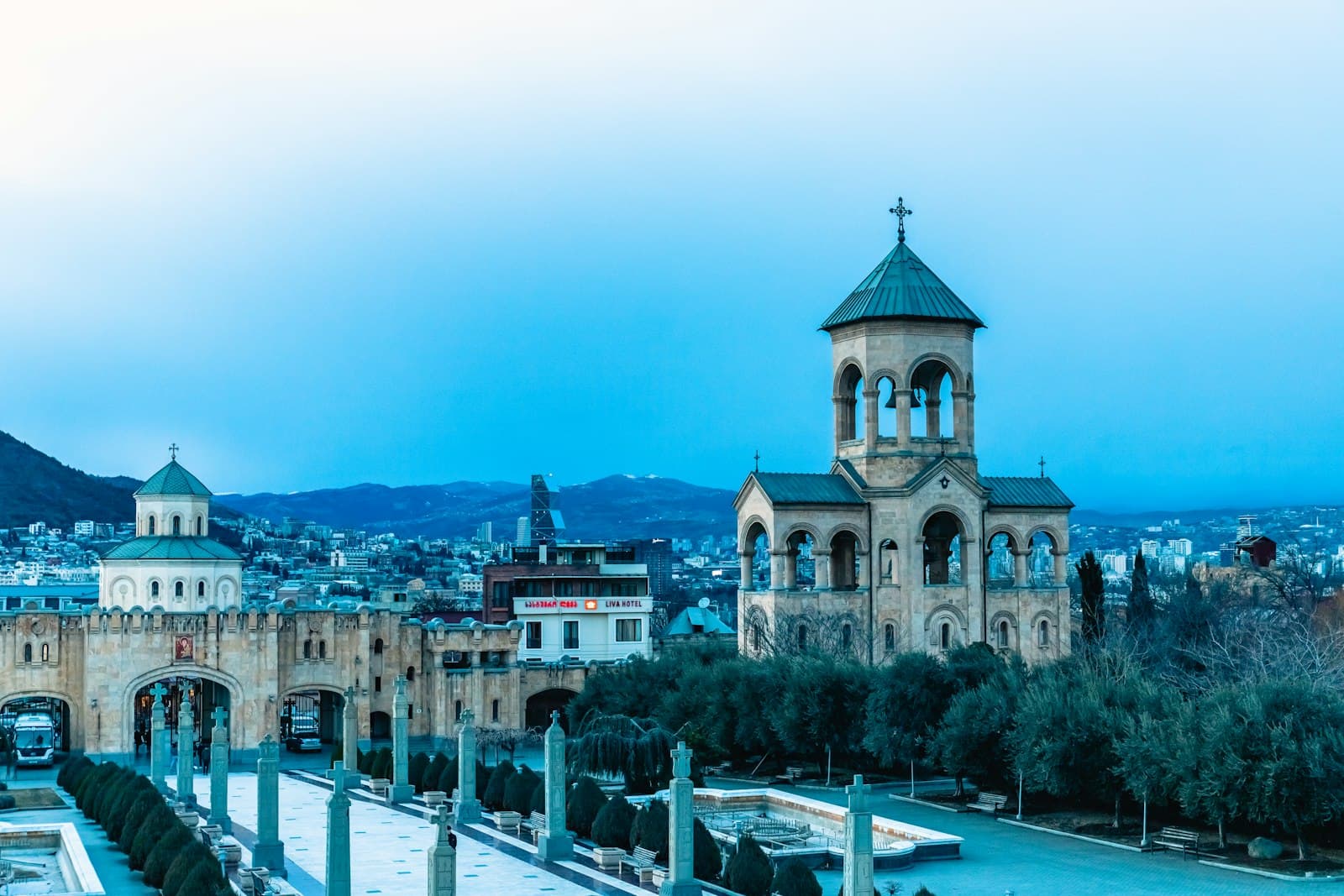 Bell tower of Holy Trinity Cathedral in Tbilisi at dusk with the city behind it