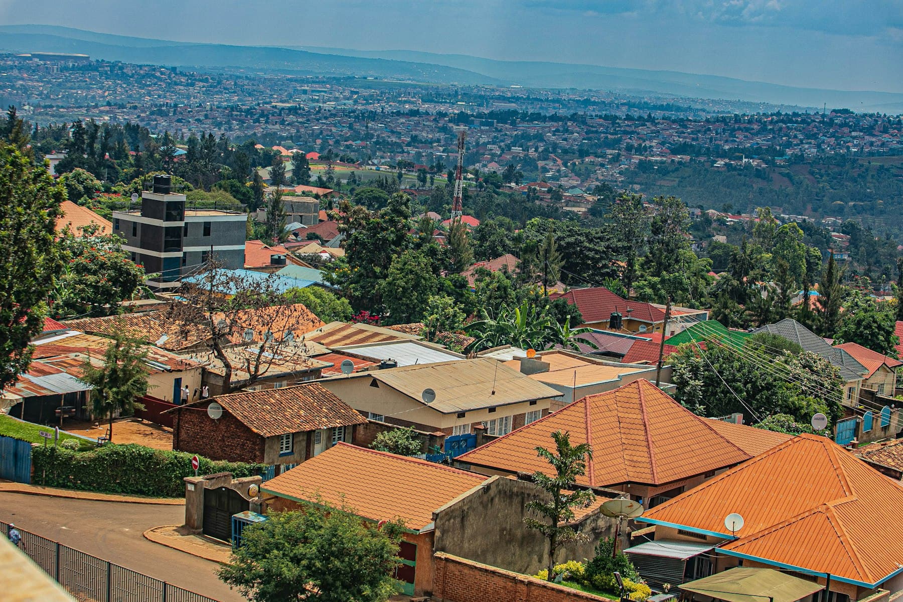 Orange-roofed homes on a Kigali hillside with the city spreading beyond