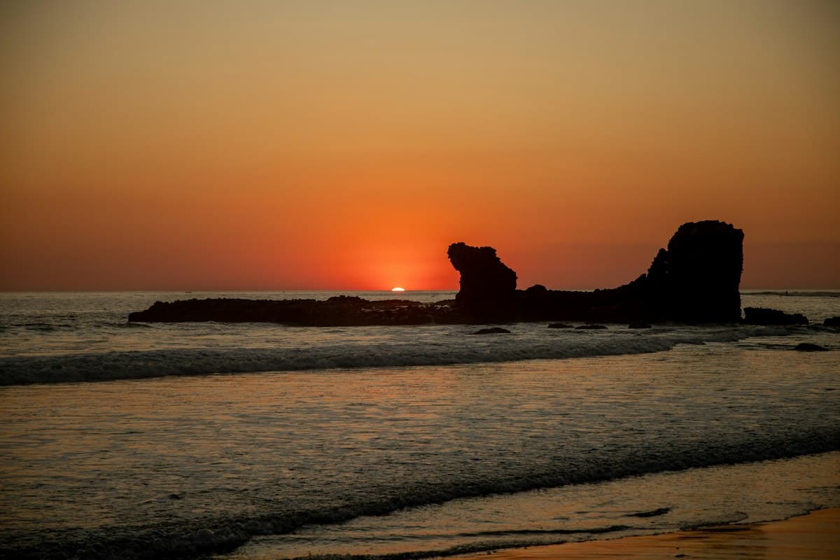 Sunset behind the rock formation off El Tunco beach on El Salvador's Pacific coast