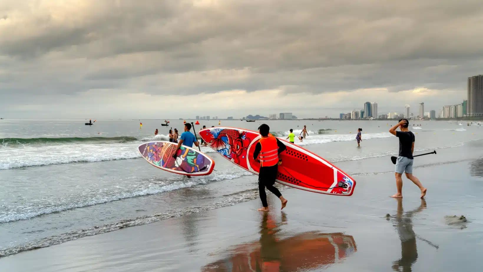 Paddleboarders carrying boards into the surf on Da Nang's city beach