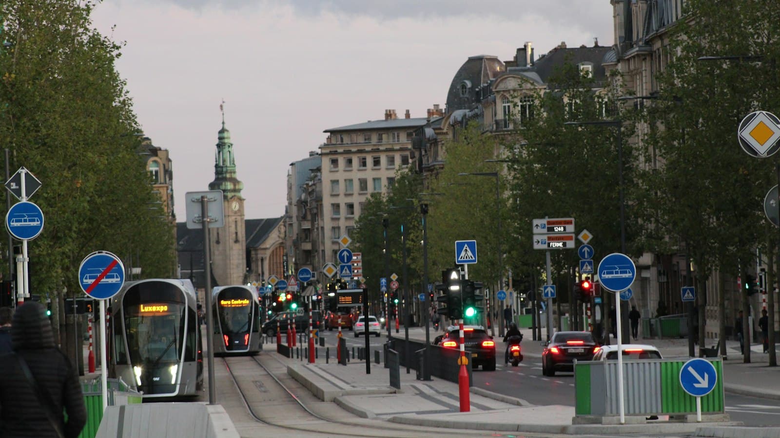 Trams on Avenue de la Liberté in Luxembourg City, with the central station clock tower behind