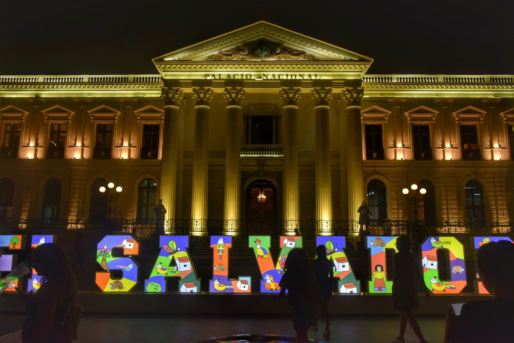 The Palacio Nacional in downtown San Salvador lit up at night behind colorful letters