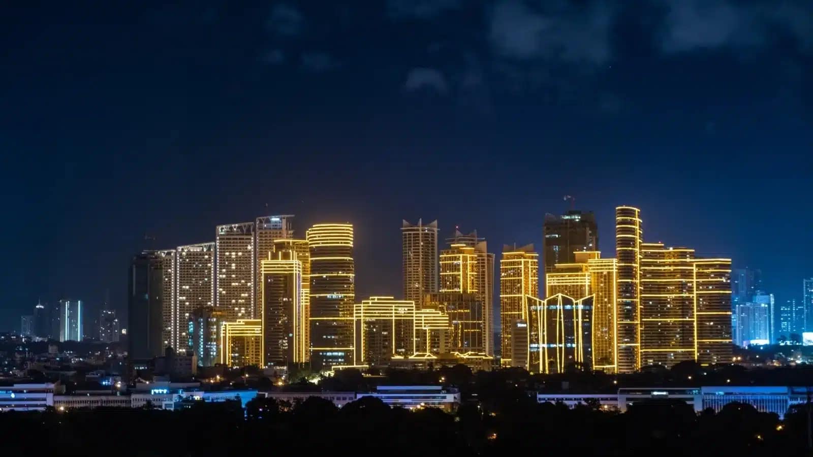 Office towers lit gold against the night sky in Metro Manila