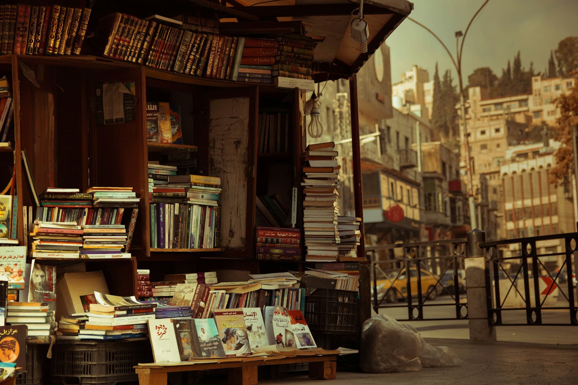 A sidewalk bookstall stacked with Arabic books on a street in Amman
