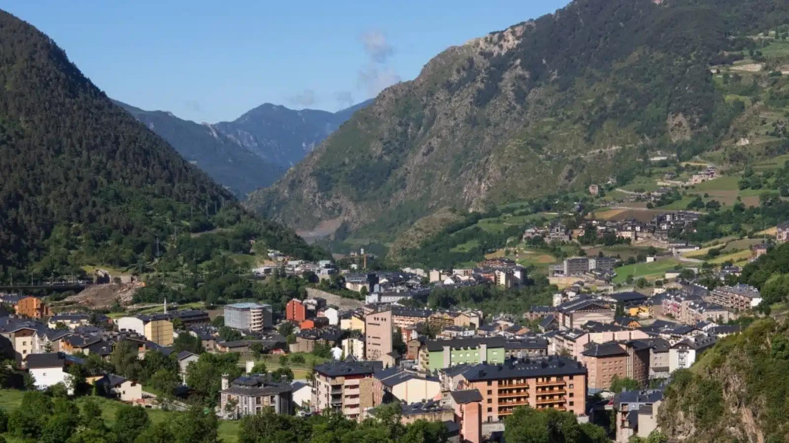 Apartment buildings spread along a green valley floor below the Pyrenees in Andorra