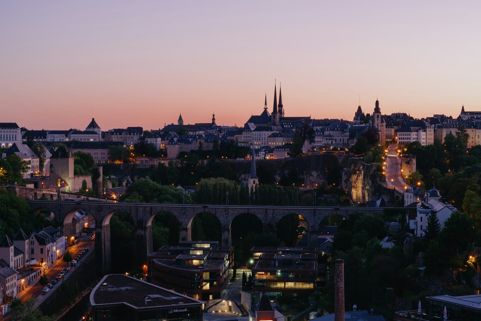 Luxembourg City's old town and cathedral spires at dusk above a stone viaduct