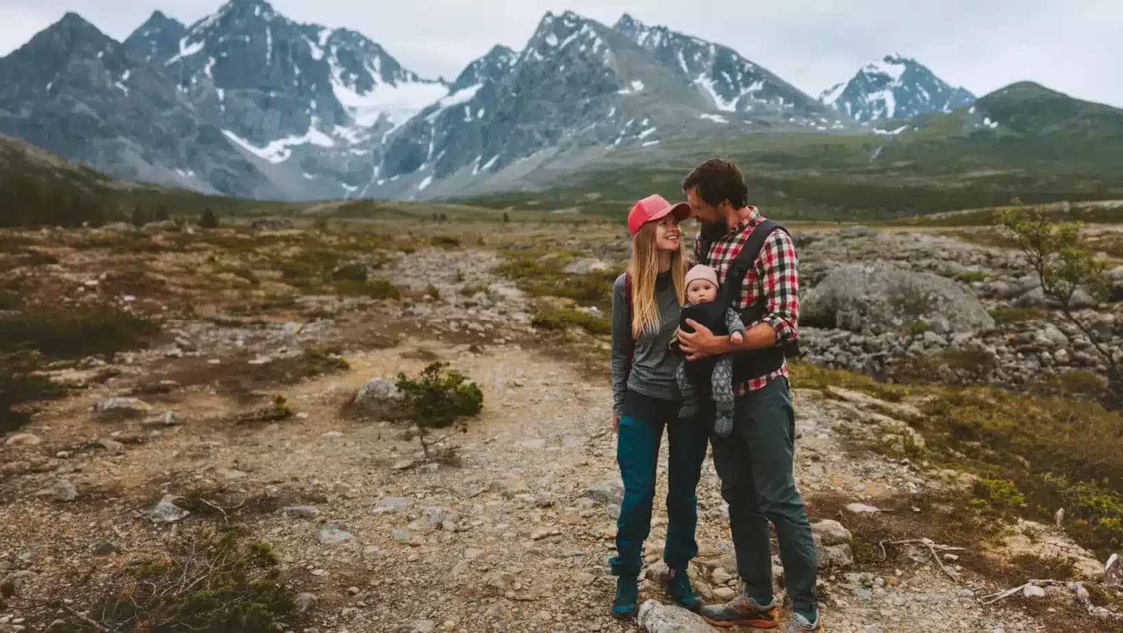 Couple with a baby in a carrier on a mountain trail in northern Norway