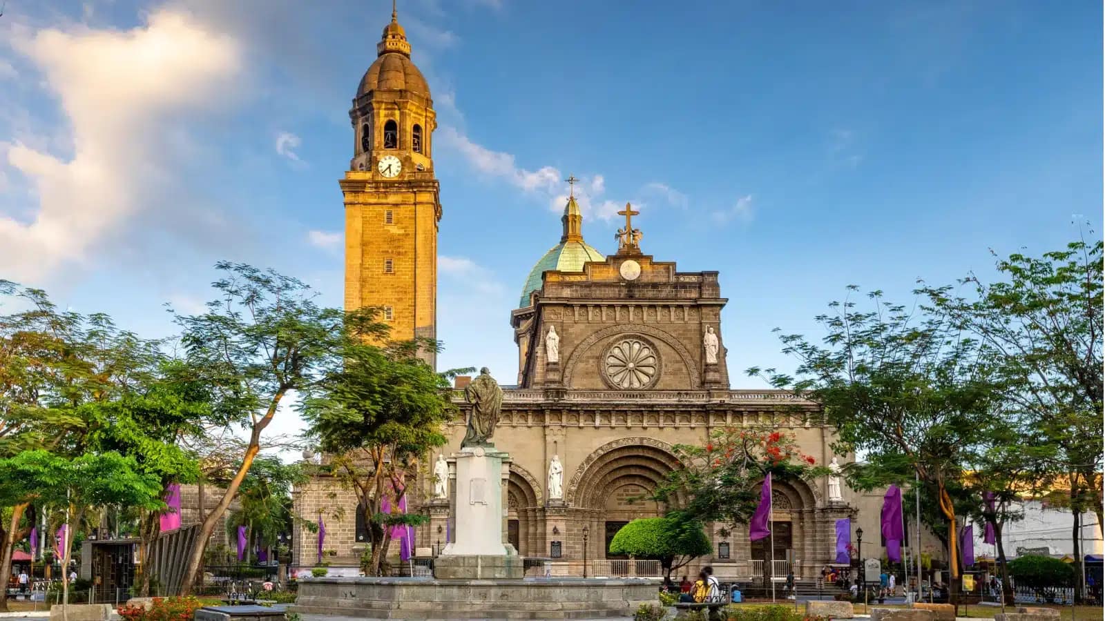 Manila Cathedral's stone facade and bell tower in Intramuros under a blue sky