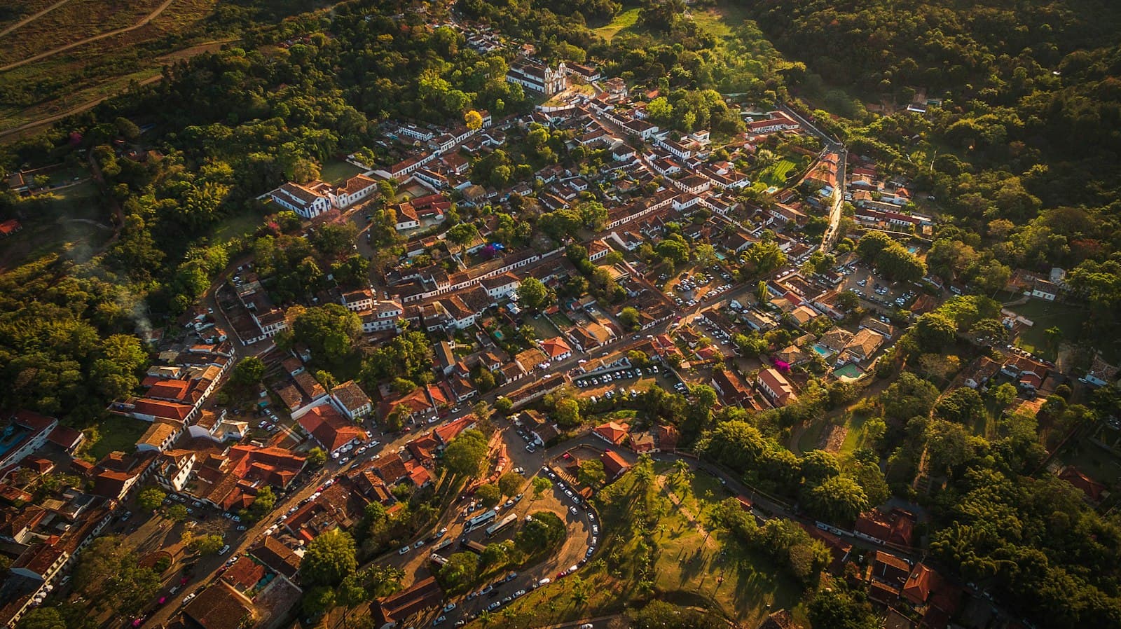 Aerial view of a small colonial town with red tile roofs surrounded by green hills in inland Brazil