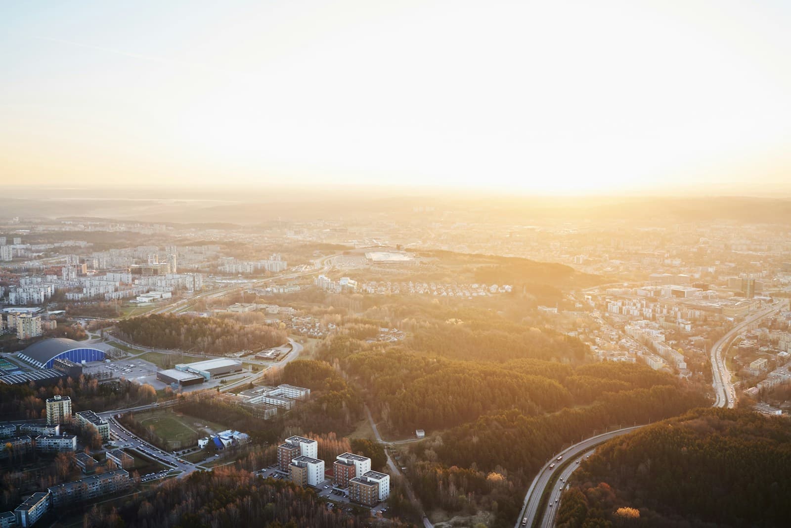 Aerial view of Vilnius neighborhoods and pine forest at golden hour