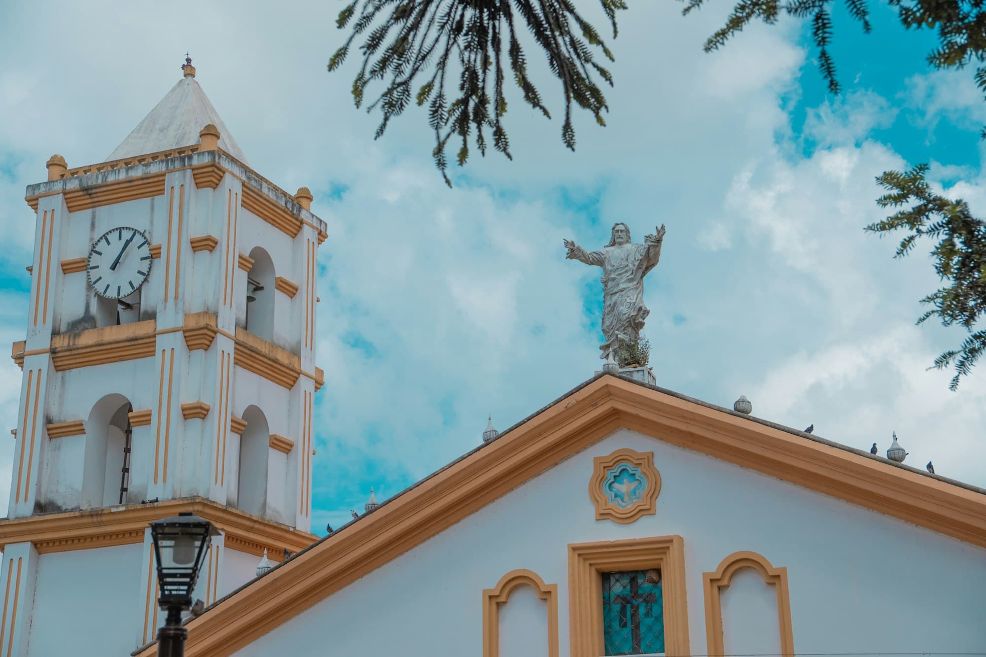 A white colonial church with a clock tower and a statue on its roof in Honduras