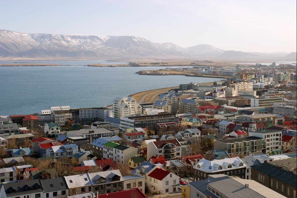 Reykjavík rooftops and the bay seen from Hallgrímskirkja, with snow on the mountains
