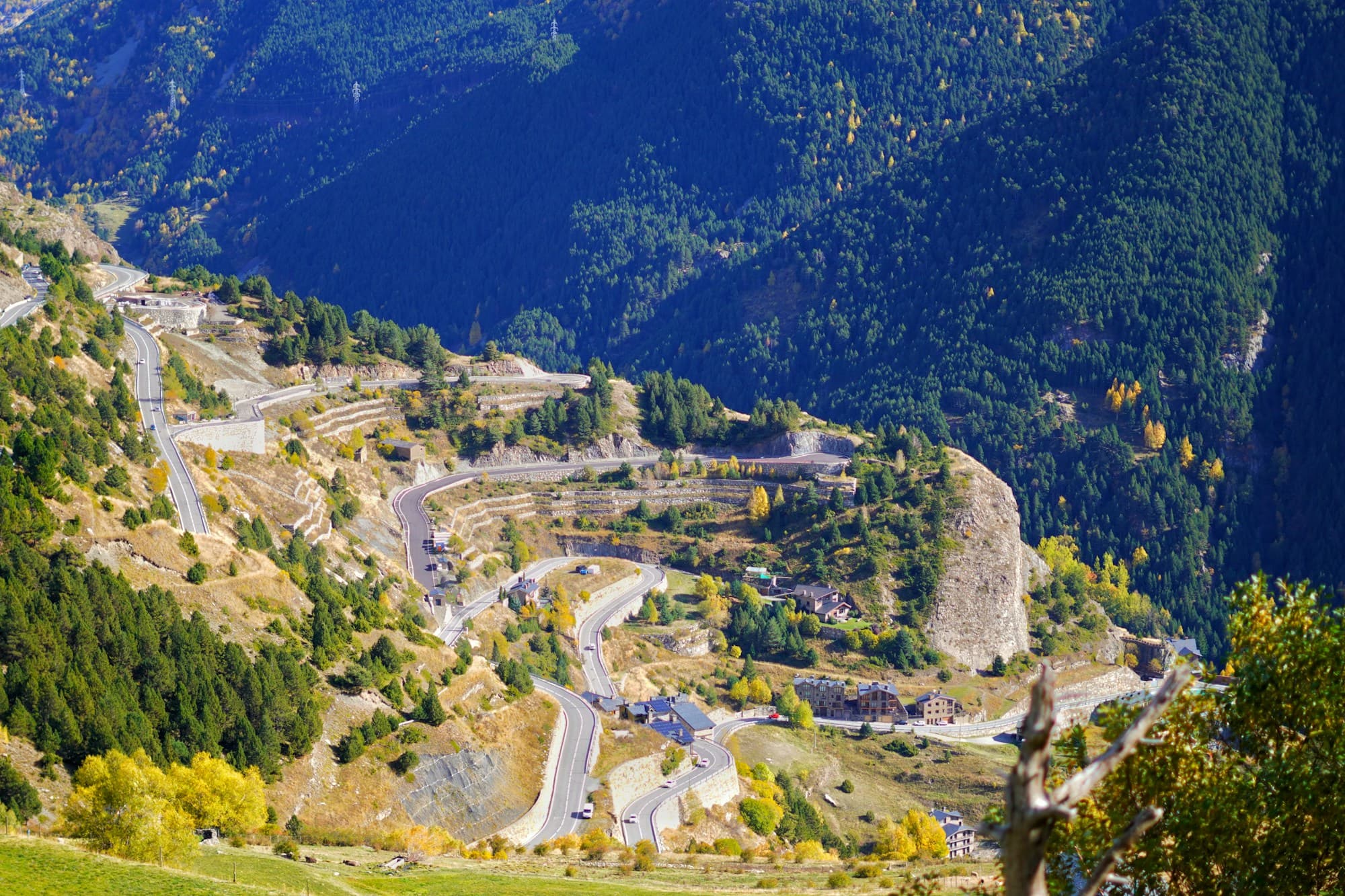 A winding mountain road with switchbacks through autumn forest in Andorra