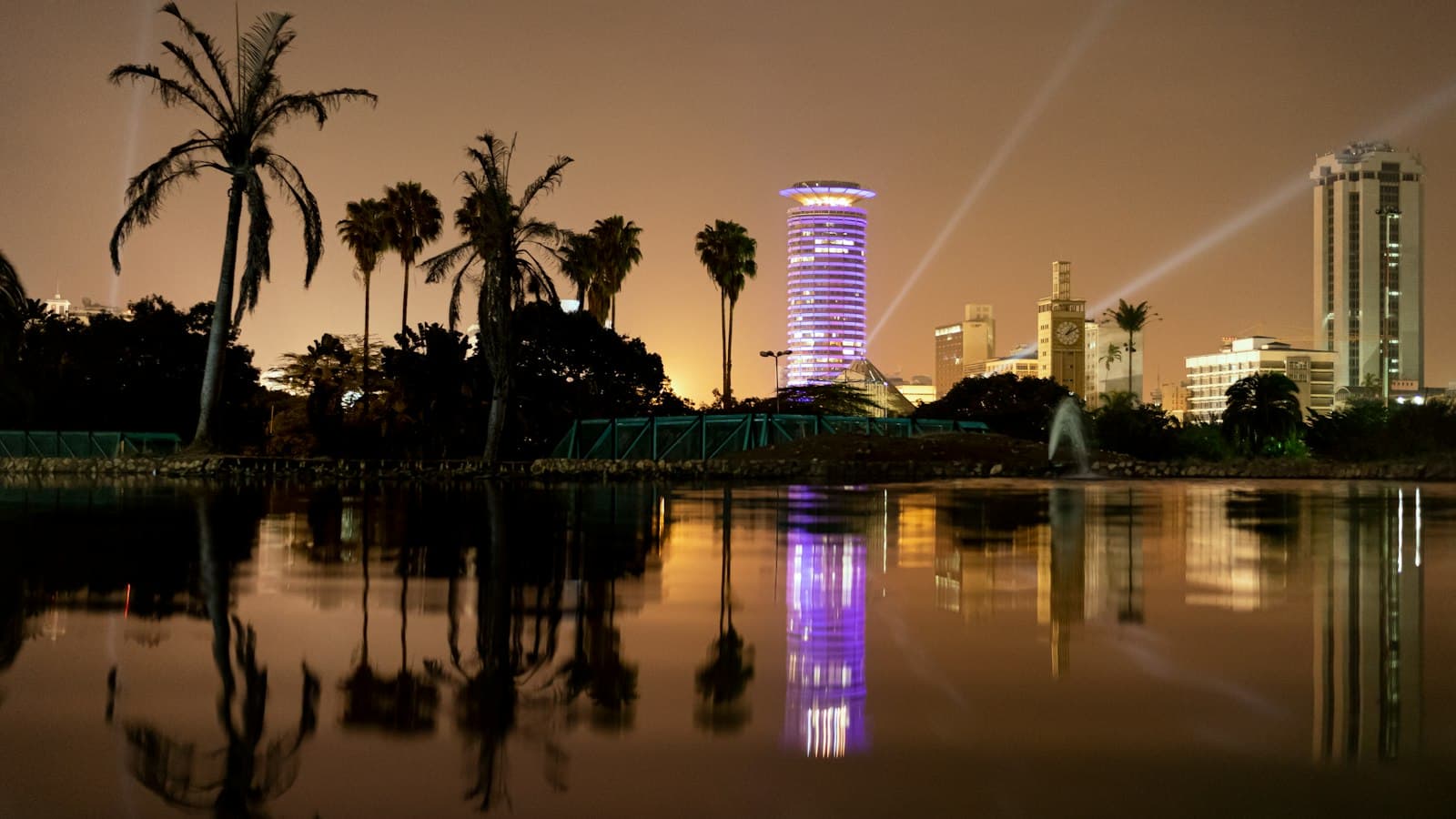 The lit-up KICC tower and Nairobi skyline reflected in a lake at Uhuru Park at night