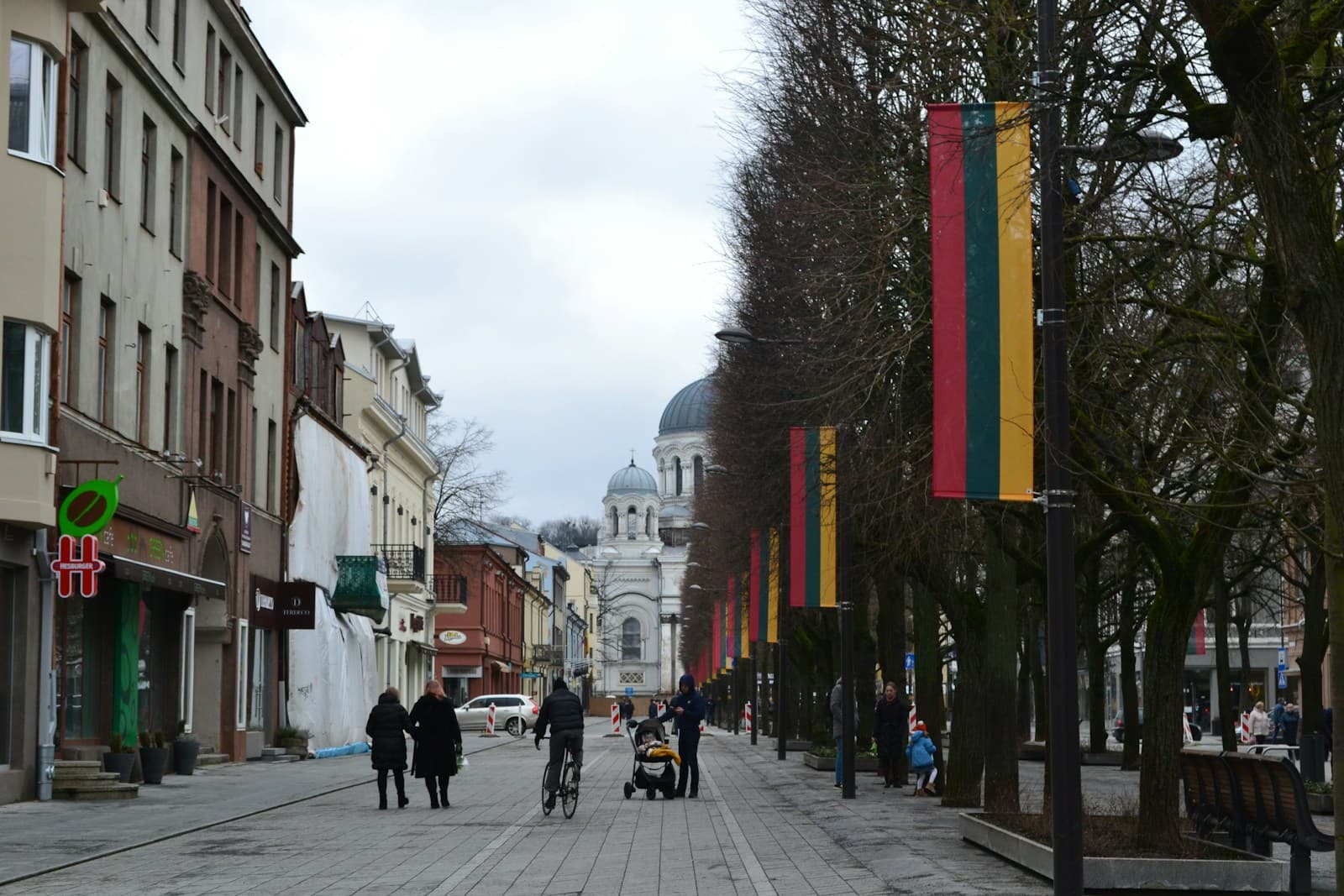 Pedestrian Laisvės alėja in Kaunas lined with Lithuanian flags, St. Michael the Archangel's Church at the end
