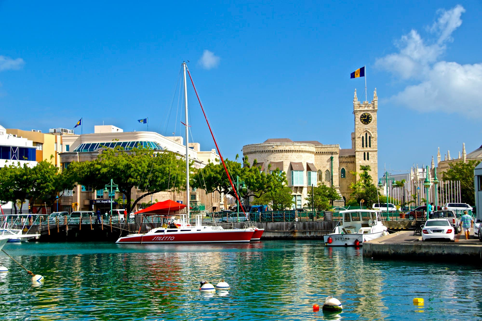 A catamaran moored in the Careenage below the Parliament clock tower in Bridgetown, Barbados