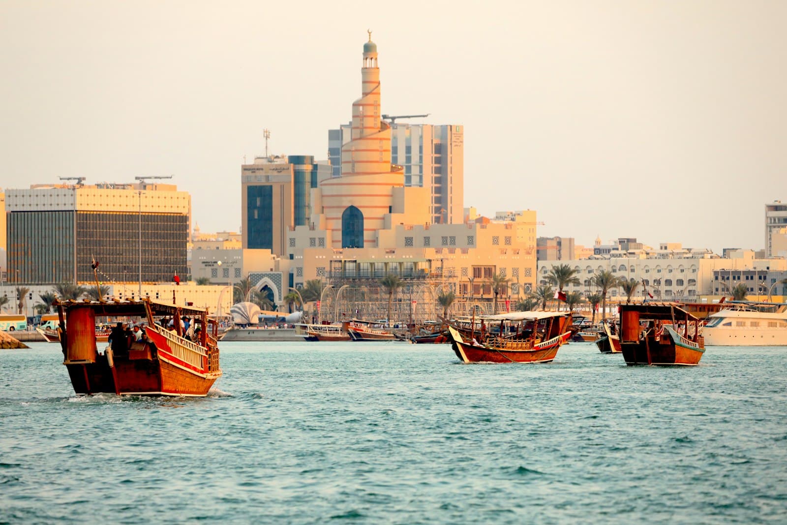 Wooden dhows on Doha Bay with a spiral minaret on the Doha skyline behind
